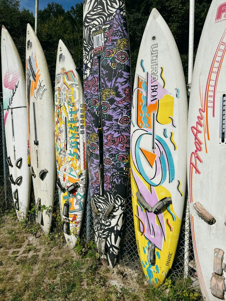 A row of vintage surfboards with vibrant designs displayed outdoors, perfect for a beach setting.